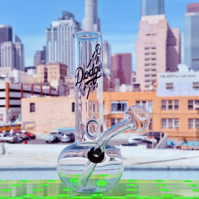 Glass pipe with 'Dodge' branding against a cityscape background