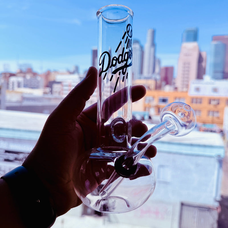 Clear glass oil burner with 'Los Angeles Dodgers' branding held against a cityscape background.