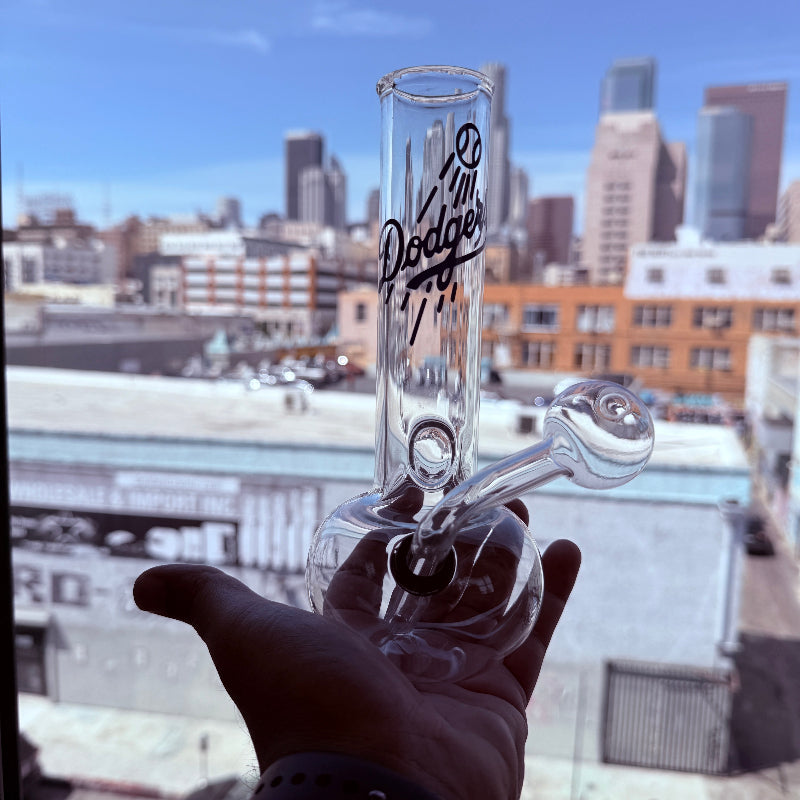 Glass pipe with 'Fruit Loops' branding held against a cityscape background