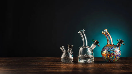 Mini, clear and hand-worked glass bubblers side by side on a wooden table