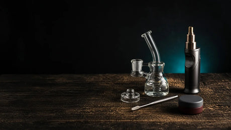 Dab rig setup with a glass rig, carb cap, dab tool, torch and wax jar