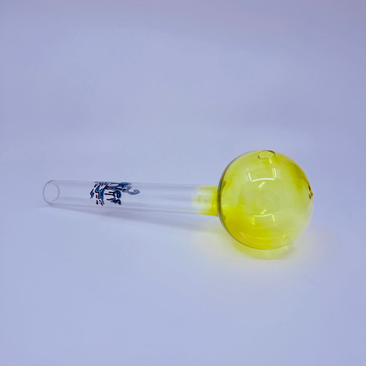 Glass smoking accessory with yellow bowl and clear base on a light gray background