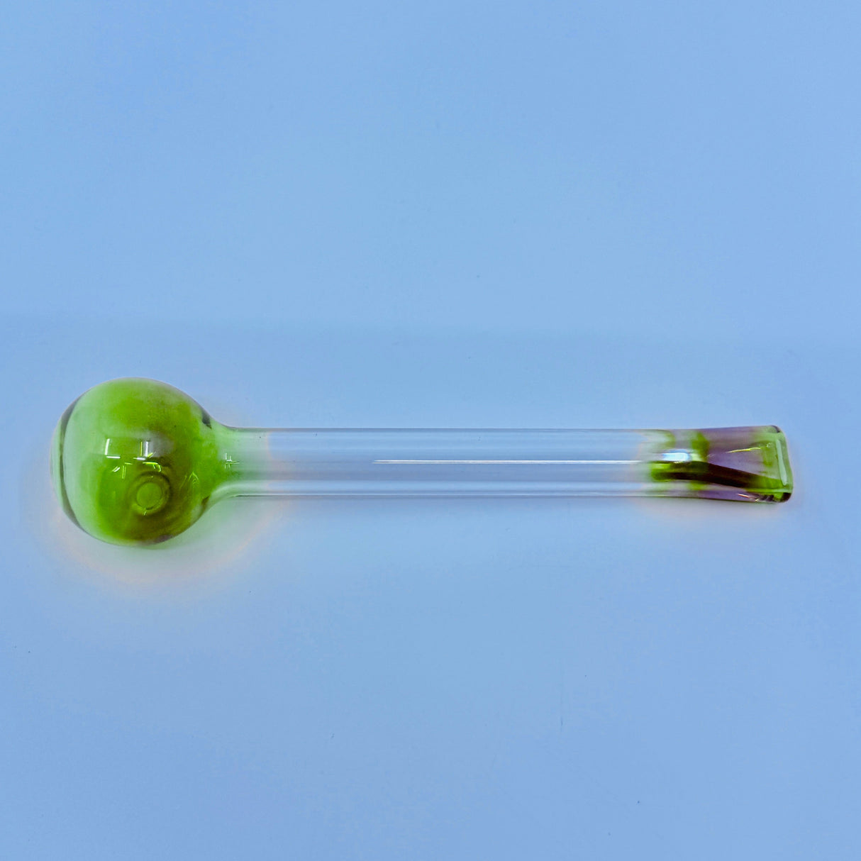 Glass smoking accessory with green bowl on a light blue background