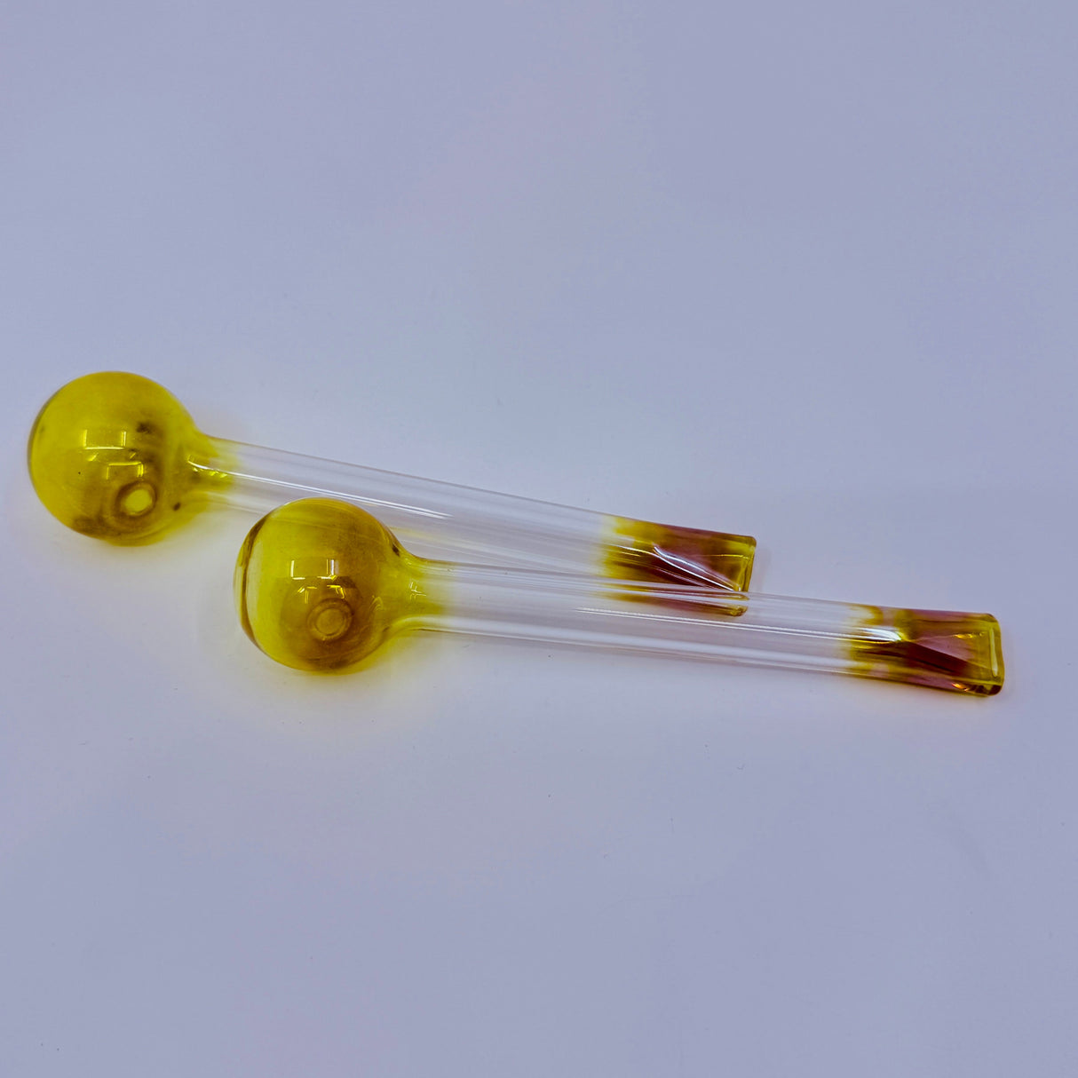 Two yellow glass vials with clear liquid on a light gray background