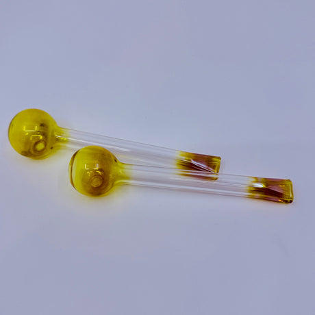 Two yellow glass vials with clear liquid on a light gray background