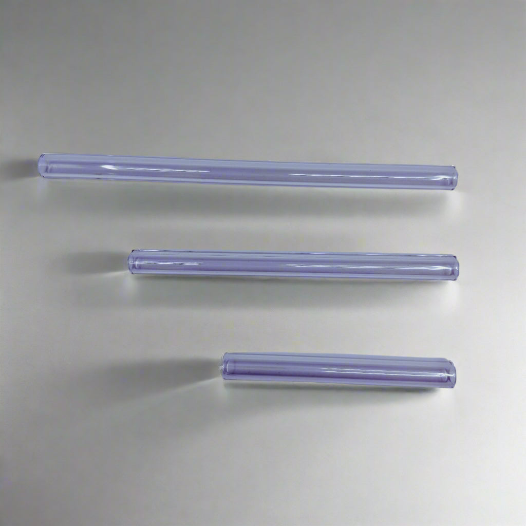 Three clear cylindrical objects on a light purple background
