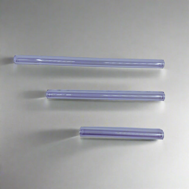 Three clear cylindrical objects on a light purple background