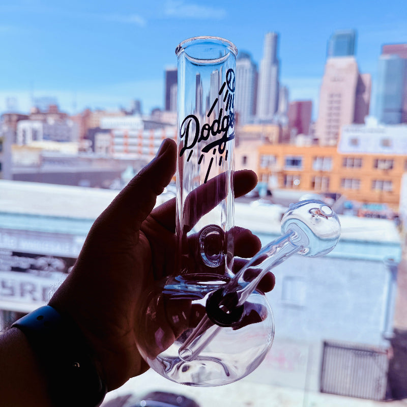 Clear glass oil burner with 'Los Angeles Dodgers' branding held against a cityscape background.