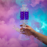 Glass smoking device with purple liquid next to a blue box with a similar design.