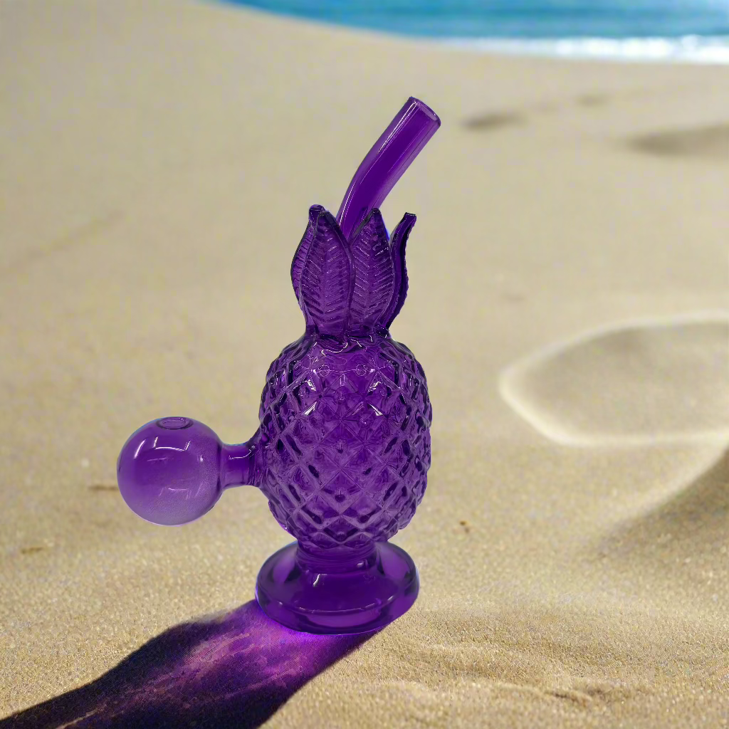 Unique 6-inch glass pineapple-shaped dab rig on sand.